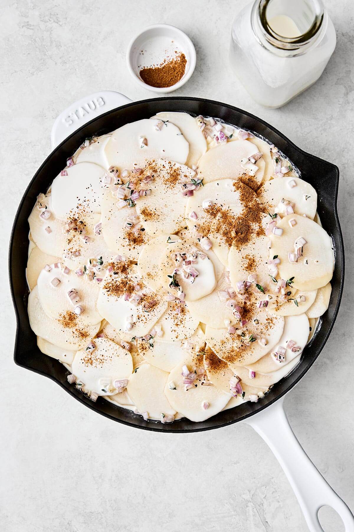 This scalloped potatoes recipe will have everyone going back for seconds! It's creamy, cheesy, and an easy side dish to make. Layering scalloped potatoes in a pan.