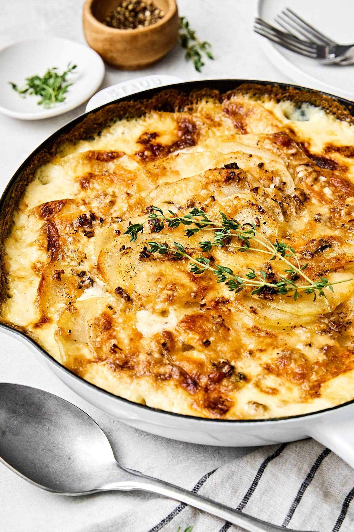 This scalloped potatoes recipe will have everyone going back for seconds! It's creamy, cheesy, and an easy side dish to make. A white pan with scalloped potatoes.