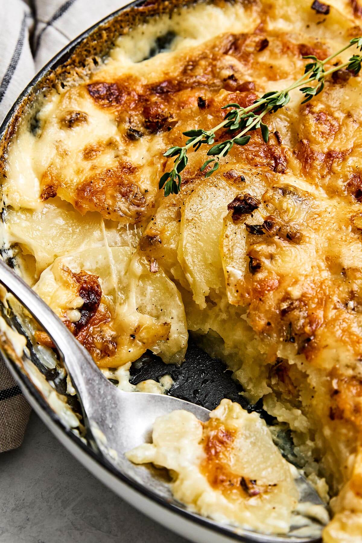 This scalloped potatoes recipe will have everyone going back for seconds! It's creamy, cheesy, and an easy side dish to make. Scooping into scalloped potatoes.