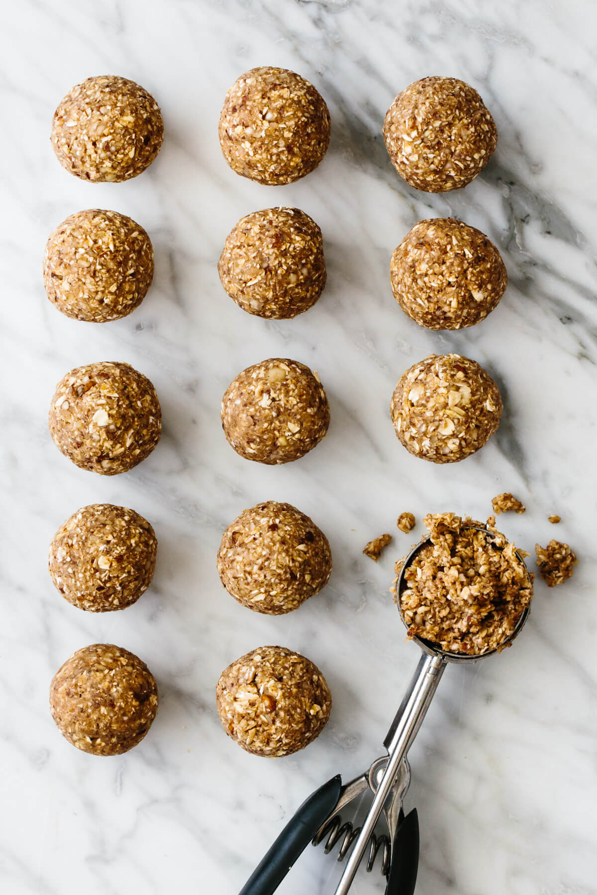 Several banana bread energy balls on a counter next to a cookie scoop.