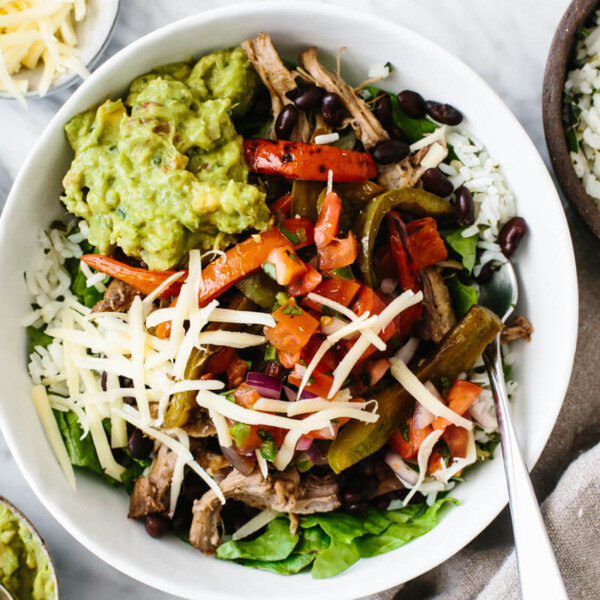 Carnitas burrito bowl surrounded by bowl of individual ingredients.