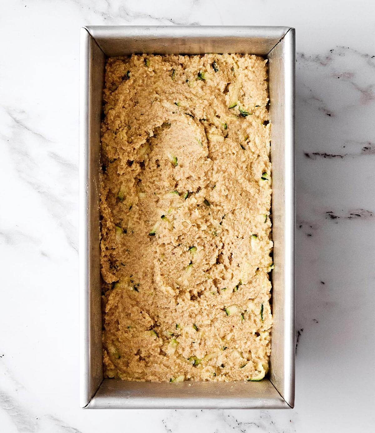 This gluten-free zucchini bread is the kind of loaf you’ll want to keep on your counter all summer long. It’s perfectly moist, gently spiced, and sneaks in a little veggie boost to your morning breakfast. Creating a zucchini bread loaf.