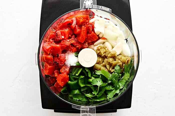 Adding salsa ingredients to a food processor.