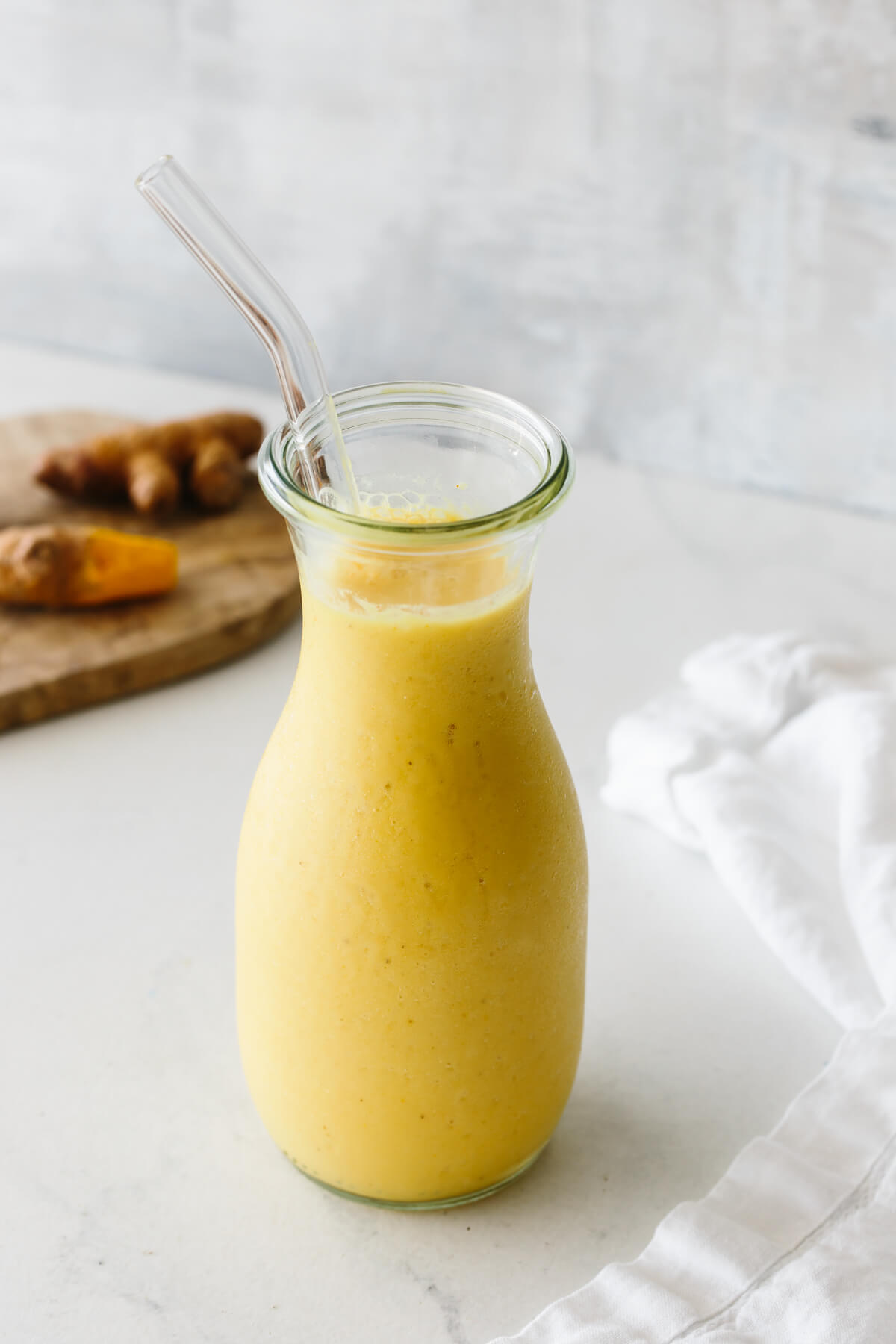 Turmeric smoothie in a glass jar with straw.