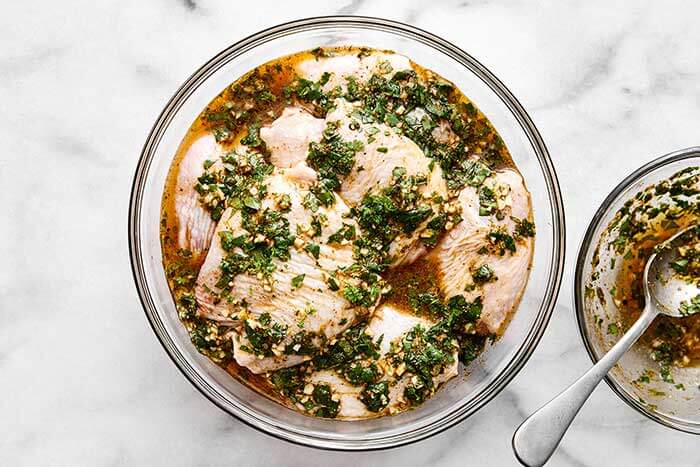 Cilantro lime chicken marinating in a glass bowl.