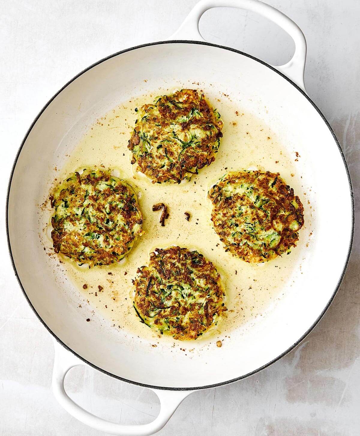 Zucchini fritters are everyone’s favorite summer dinner. With savory flavors, crispy edges, and a dollop of creamy garlic chive yogurt sauce, it's the perfect zucchini recipe to keep in rotation! Pan-frying zucchini fritters.
