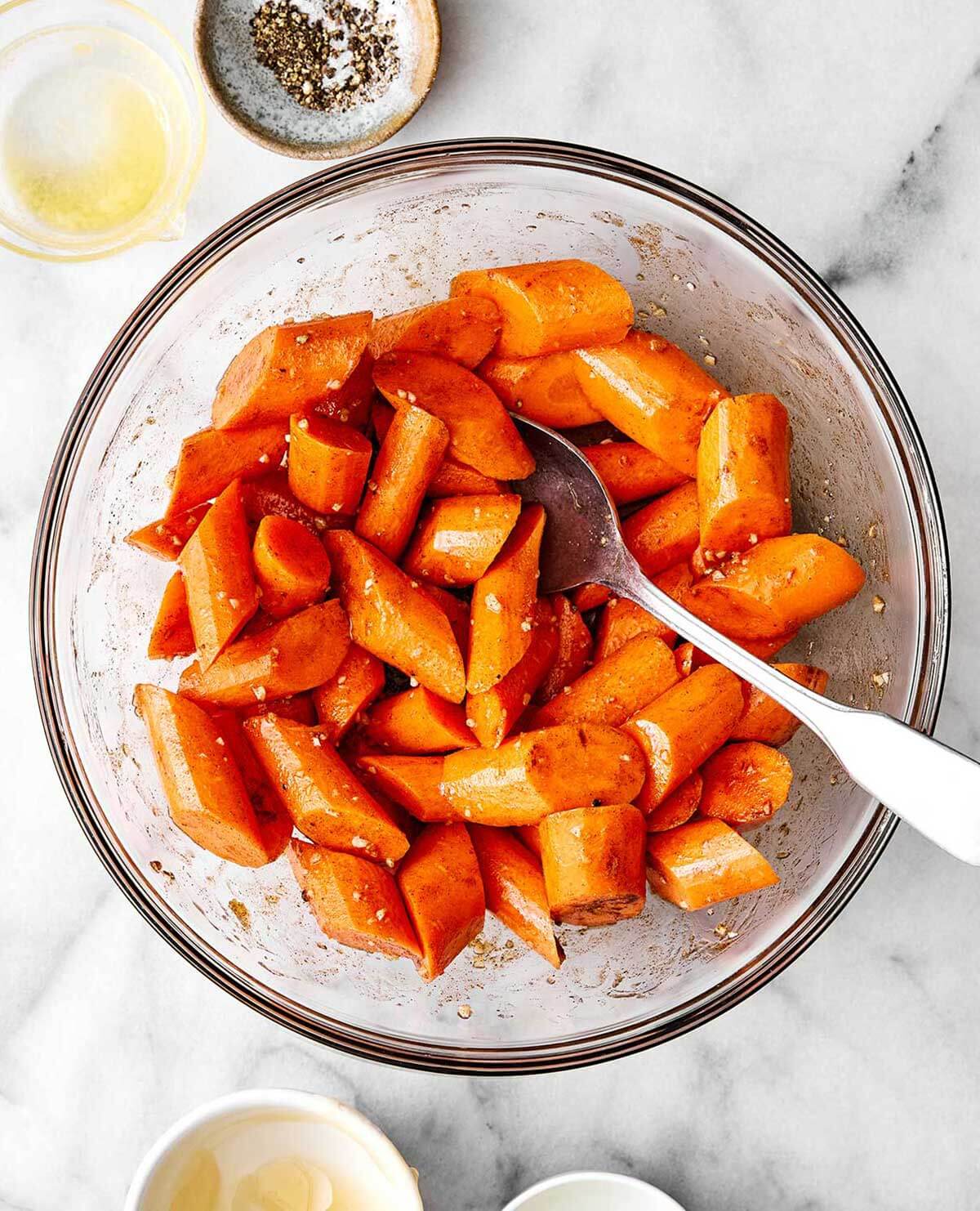 Tossing honey glazed carrots in a bowl.