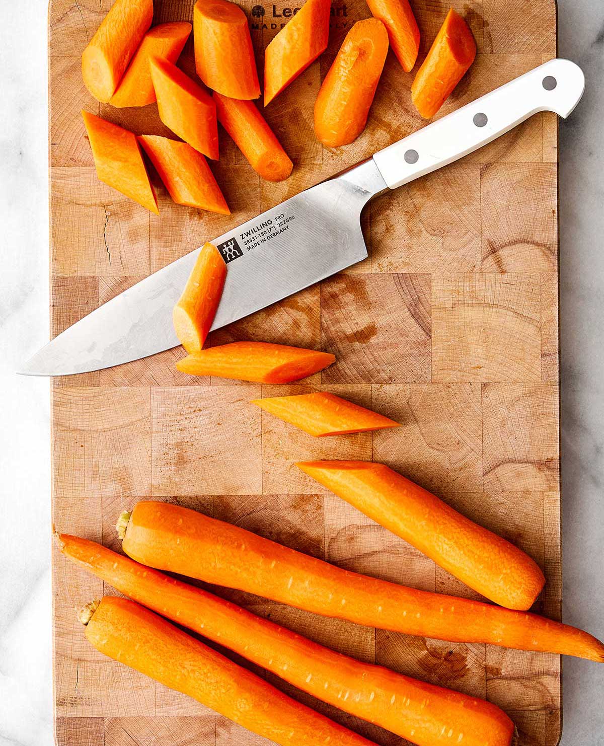 Dicing carrots on a board.