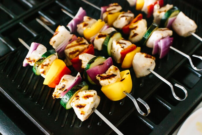 A grill with chicken kabob skewers