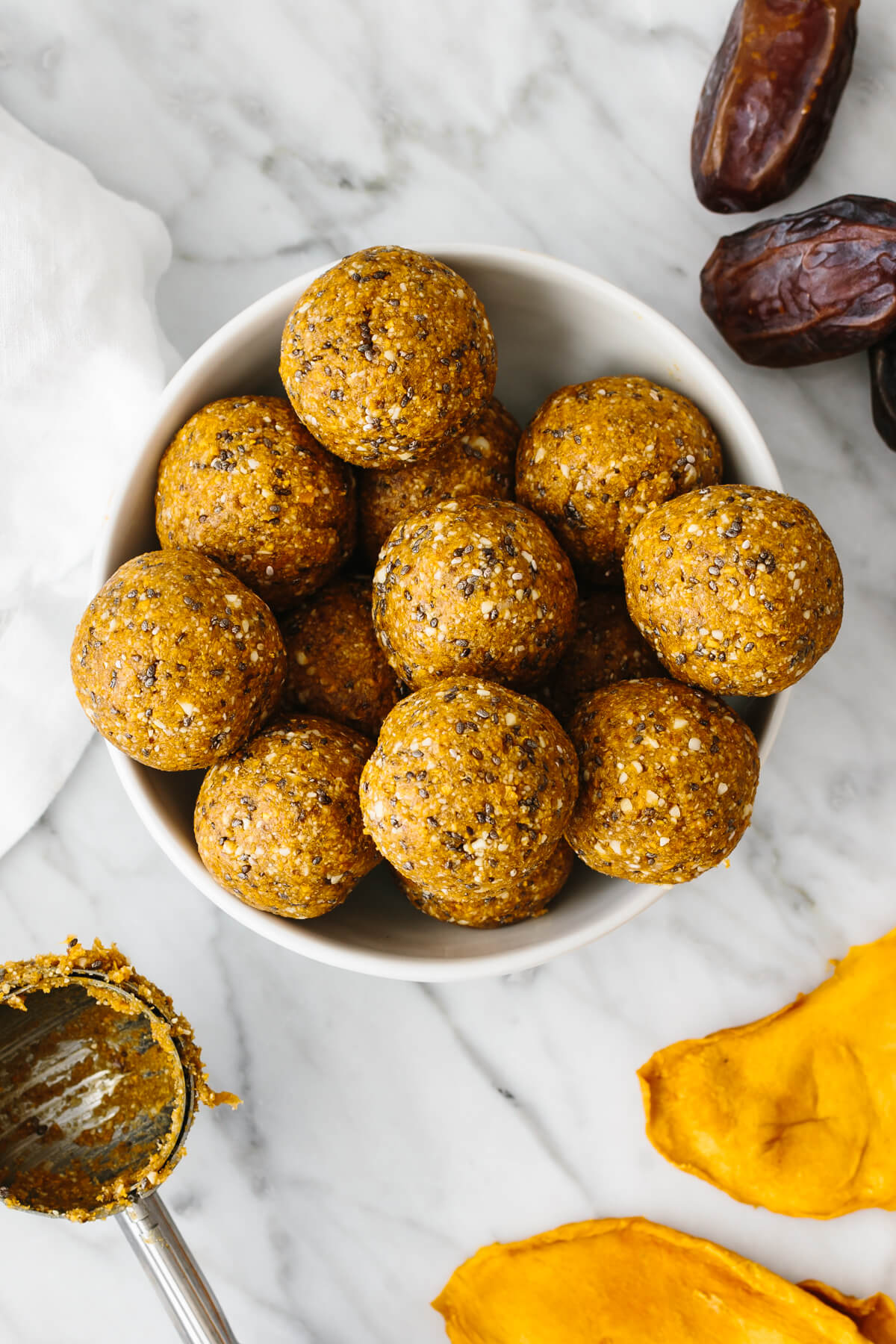 A bowl of mango date energy balls on a table.