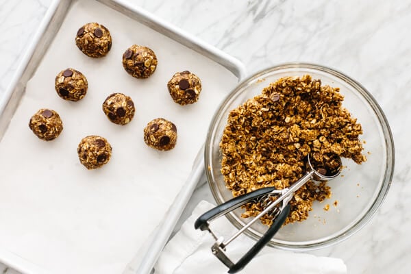 Chocolate chip energy balls next to a bowl with its ingredients.