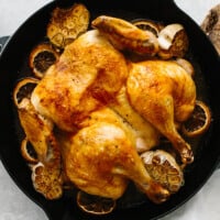 Lemon garlic spatchcock chicken in a pan next to a knife.
