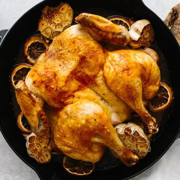 Lemon garlic spatchcock chicken in a pan next to a knife.