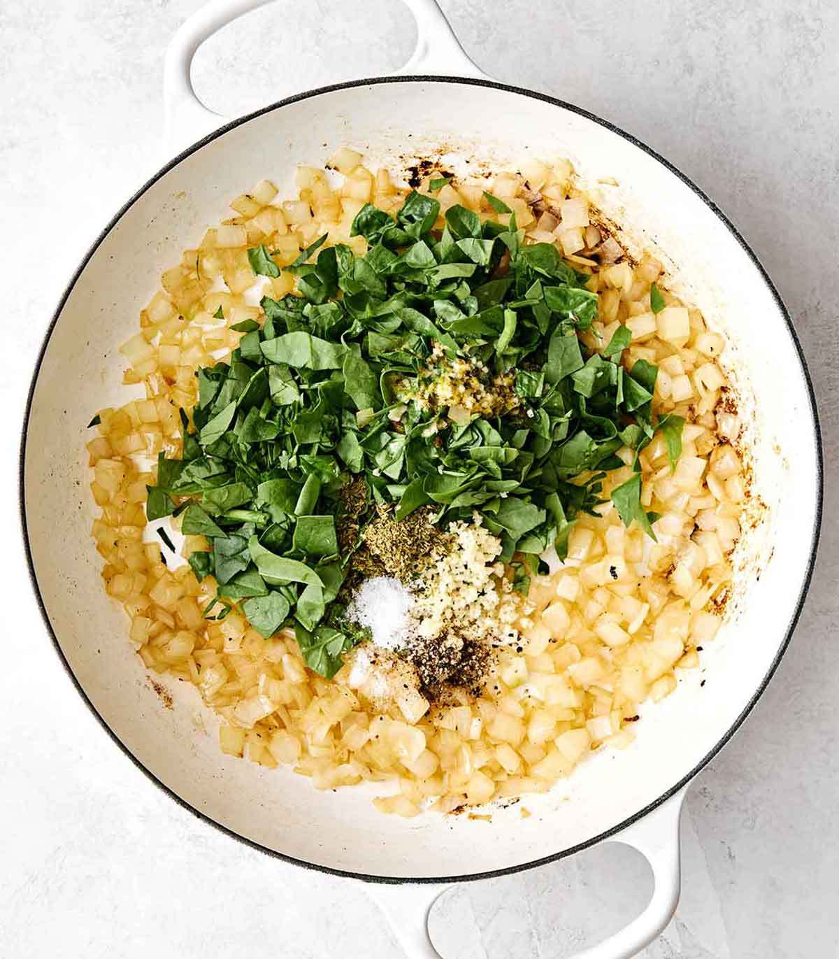 Cooking onions with herbs in a pan.