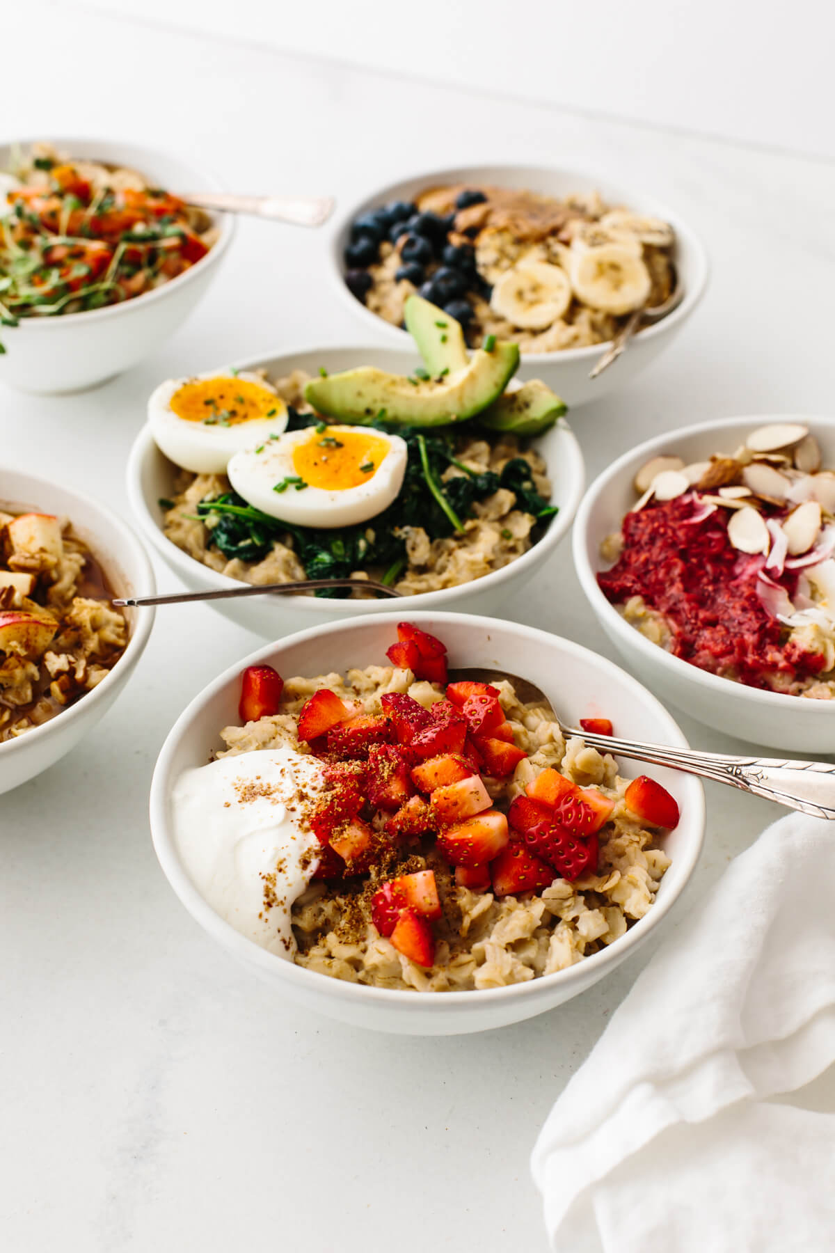 Bowls of oatmeal recipes on a table next to a napkin.