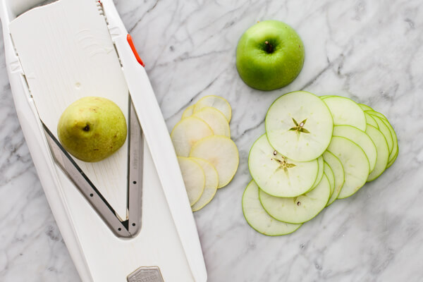 Slicing apples and pears with a mandoline for a white Christmas sangria.