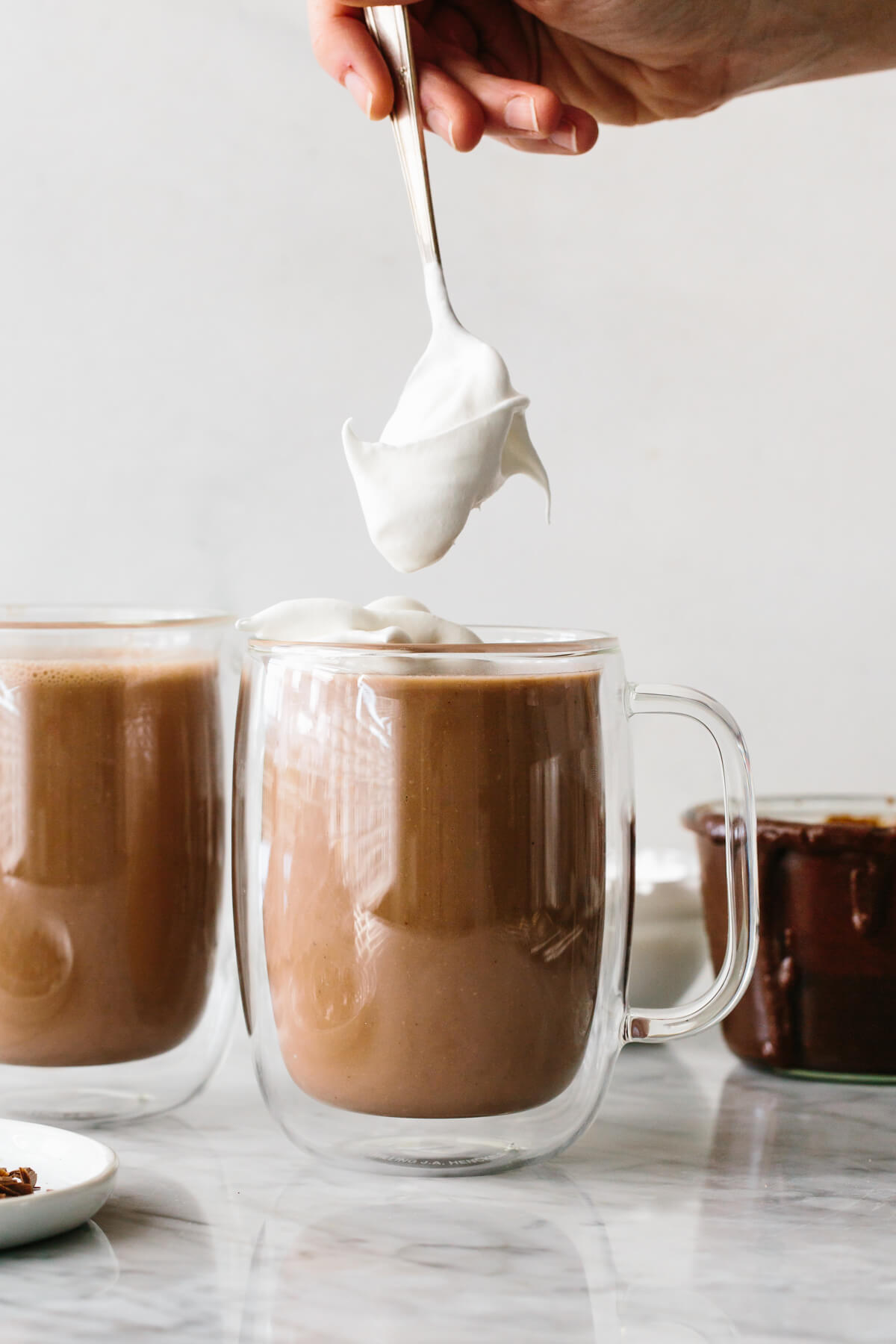 Adding whipped cream on top of Nutella hot chocolate.