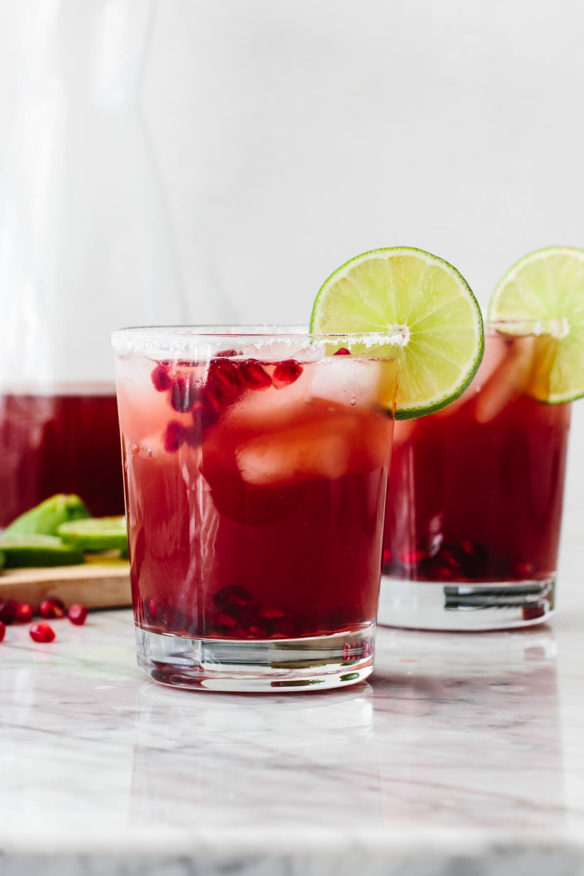 Two glasses of pomegranate margarita on a table.