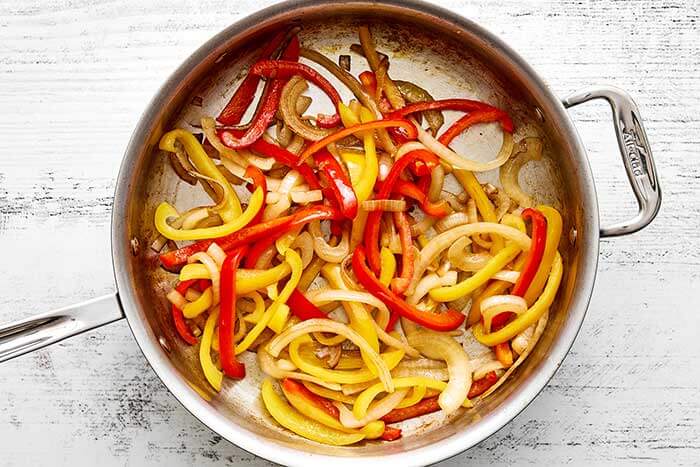 Cooked bell peppers and onions in a skillet.