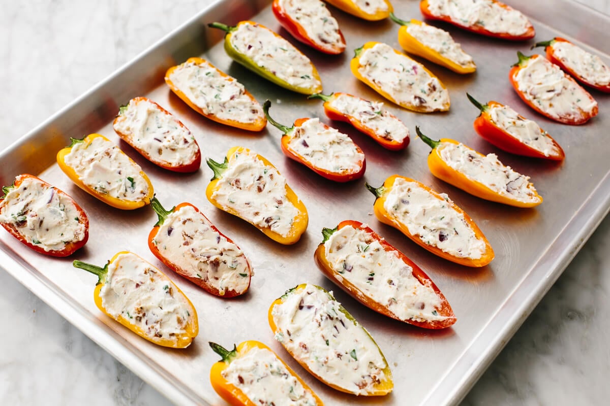 Bacon goat cheese stuffed mini peppers on a baking sheet.