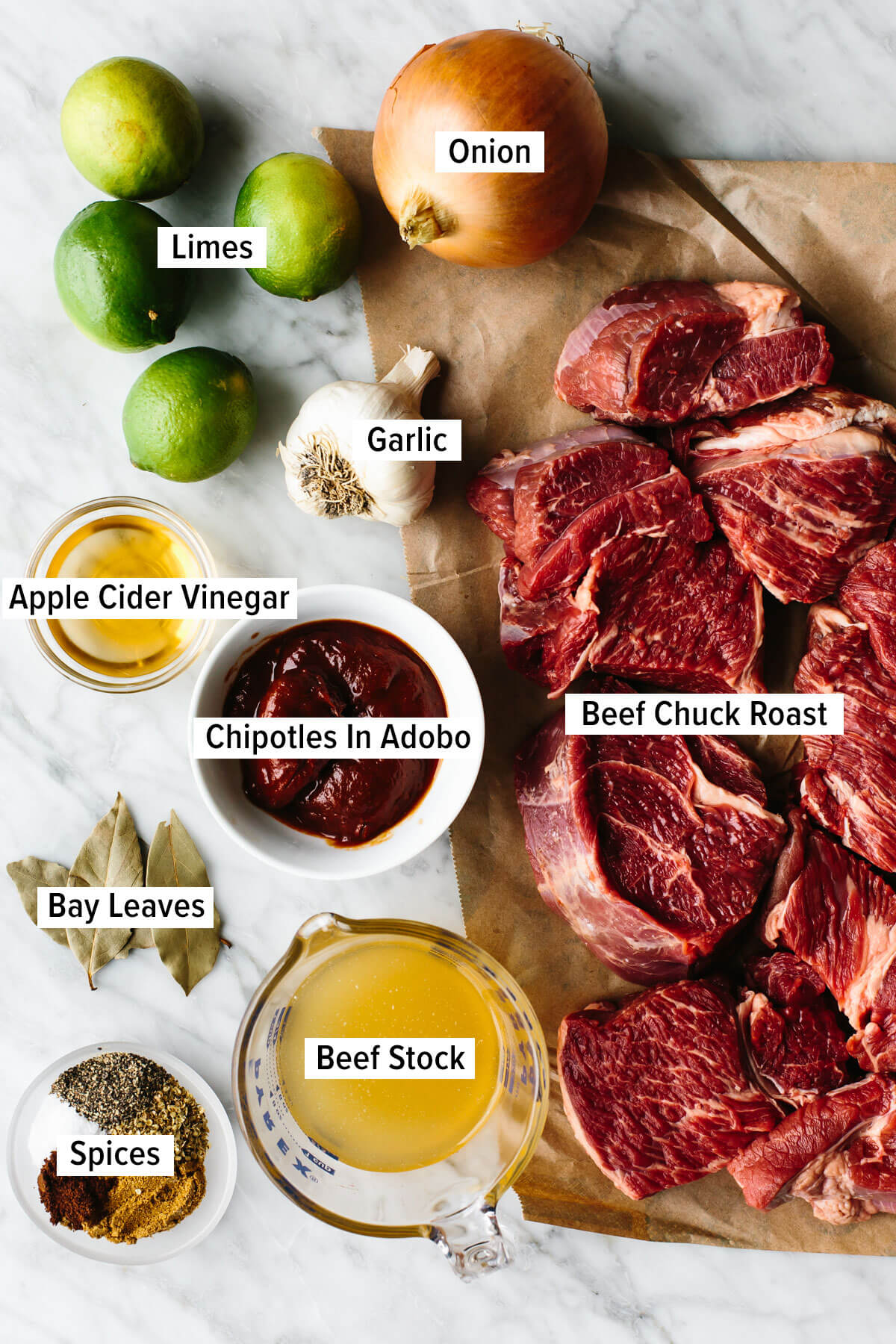 Mexican beef barbacoa that's juicy, meltingly tender, seasoned with flavorful chilies and spices, and made easy right in the slow cooker! Ingredients for beef barbacoa on a table.