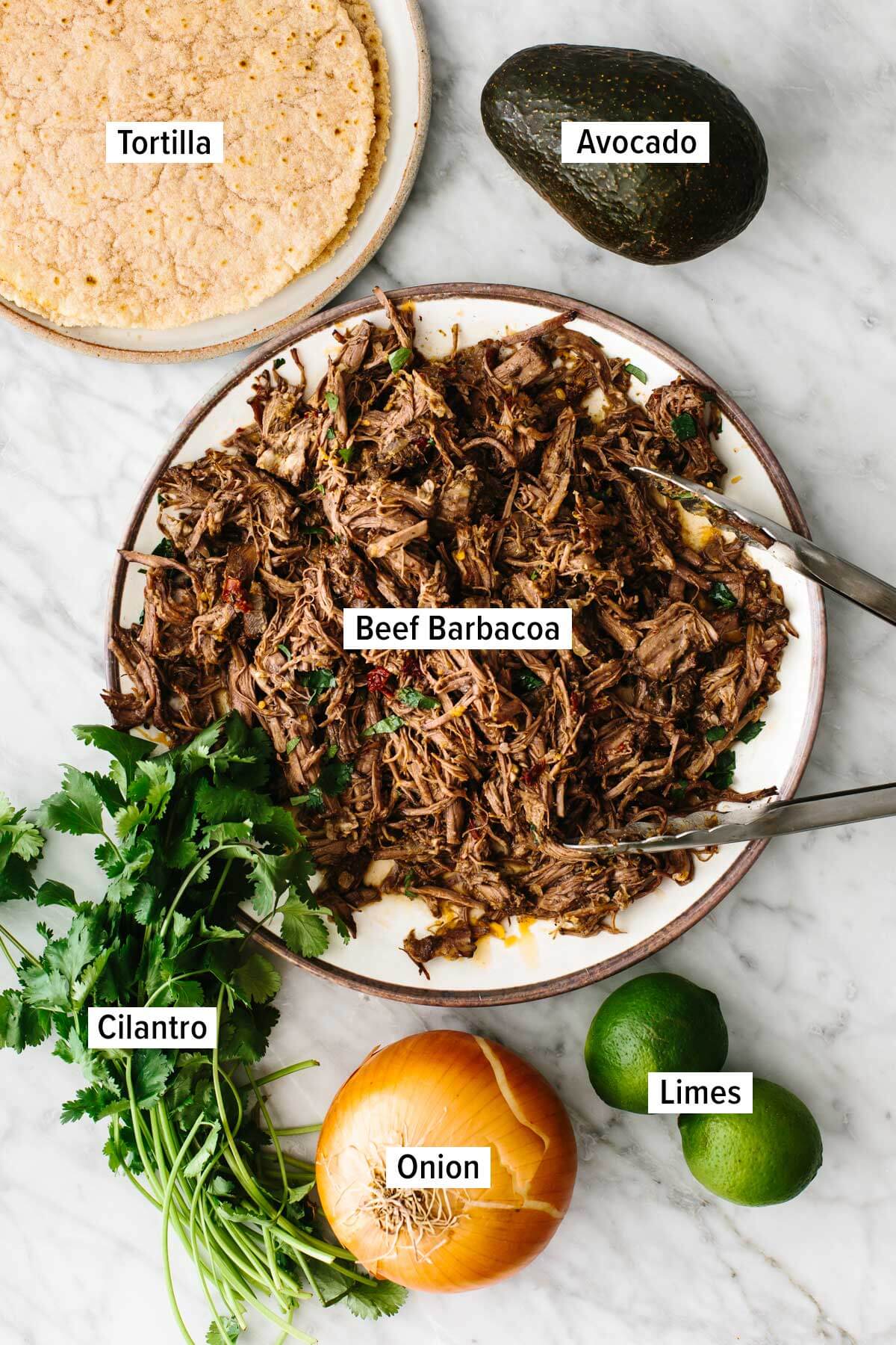 Ingredients for beef barbacoa tacos on a table.