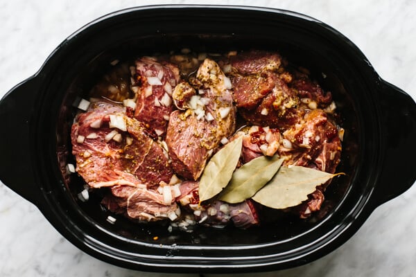 Mixing beef barbacoa ingredients in a slow cooker.