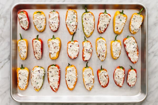 Stuffed mini peppers laid out on a baking sheet.