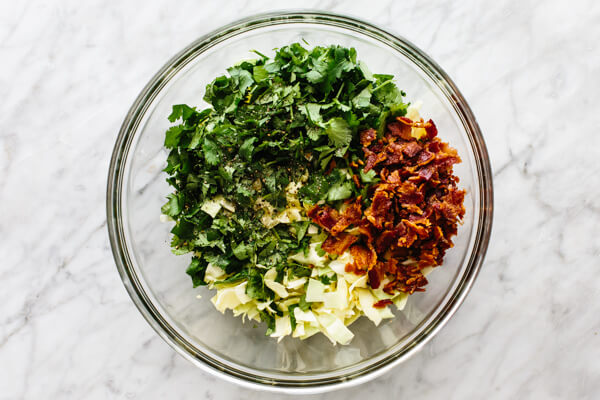 Mixing cilantro lime bacon coleslaw in a bowl.