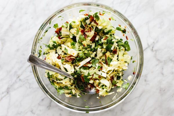 Tossing together cilantro lime bacon coleslaw in a bowl.