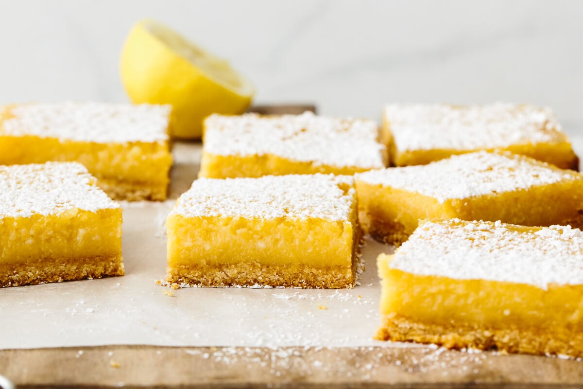 These lemon bars have a gluten-free shortbread-like crust and a bright, luscious filling that's the perfect balance of sweet and tangy! A wooden board with gluten-free lemon bars