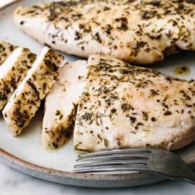 A plate of herb baked chicken breast slices.