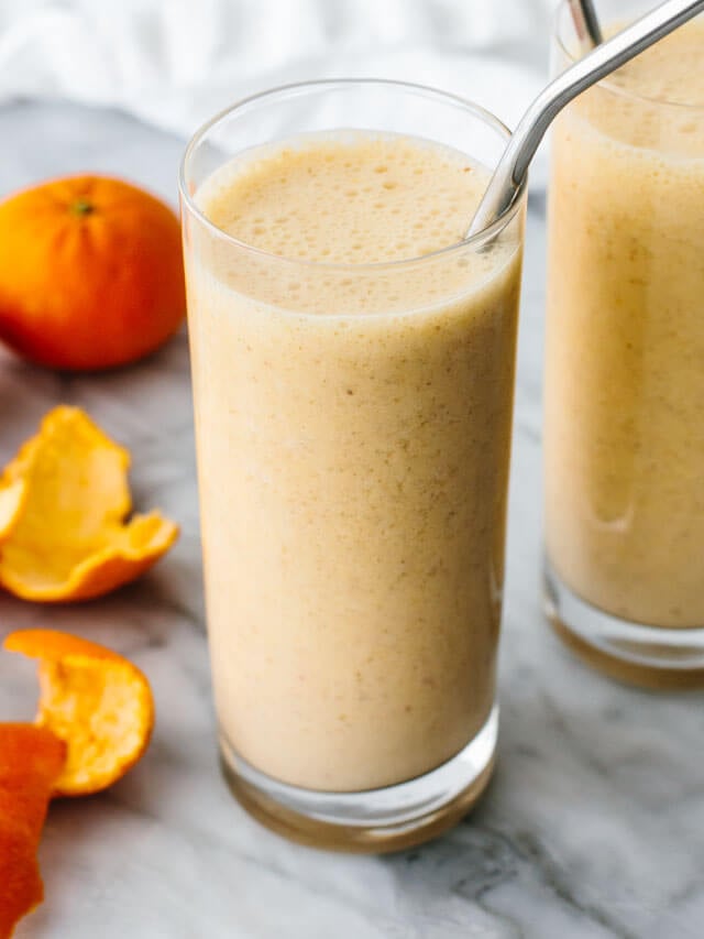 Mandarin breakfast smoothie in a glass next to mandarins