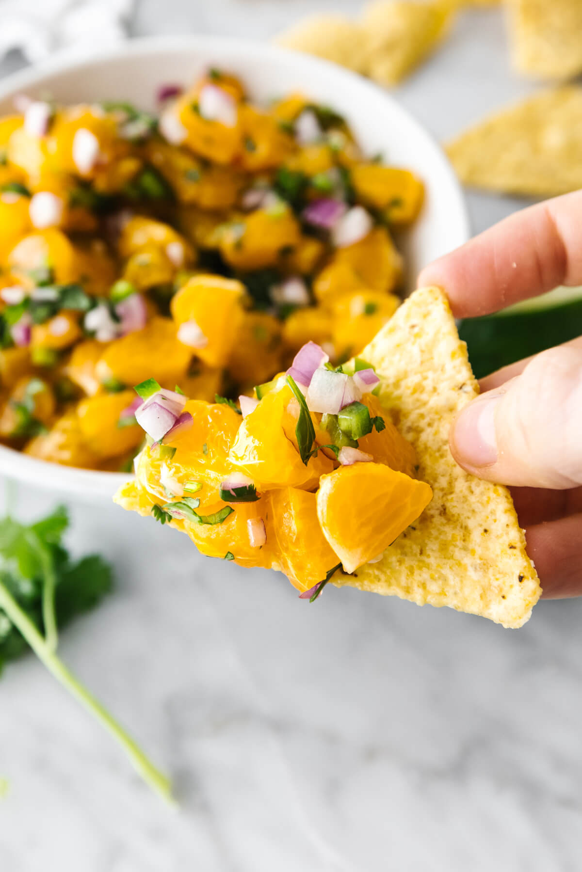 Scooping up mandarin orange salsa with a tortilla chip.