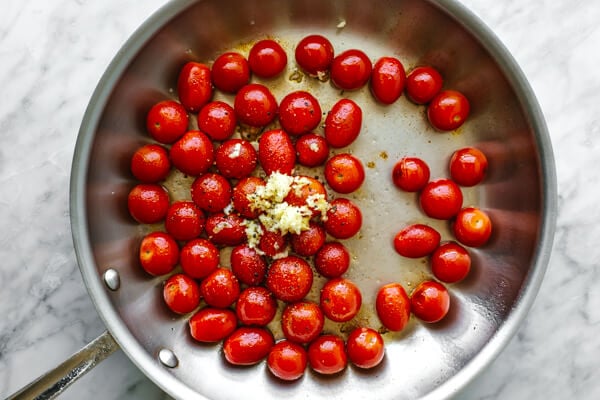 Cooking cherry tomatoes in a pan for blistered tomatoes.