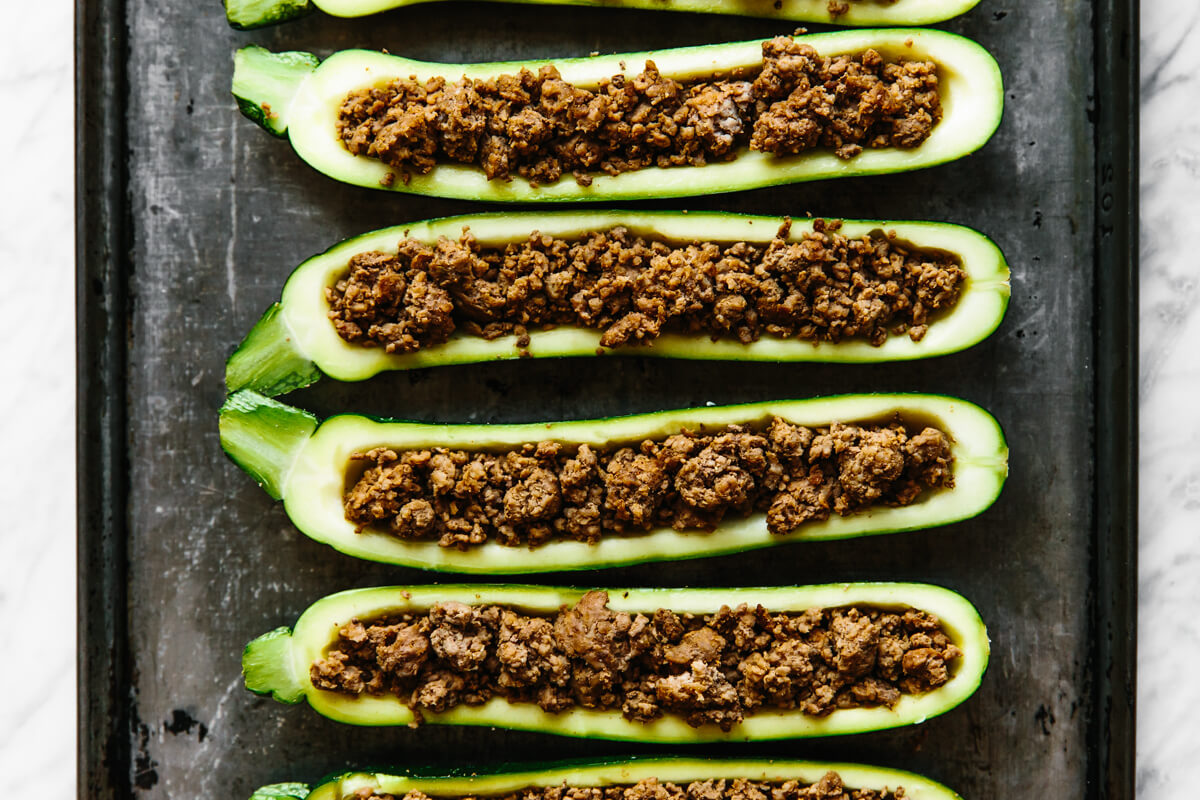 Filling zucchini boats with ground beef.