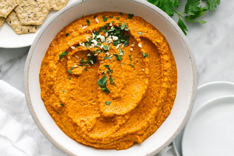 A bowl of romesco sauce next to white plates