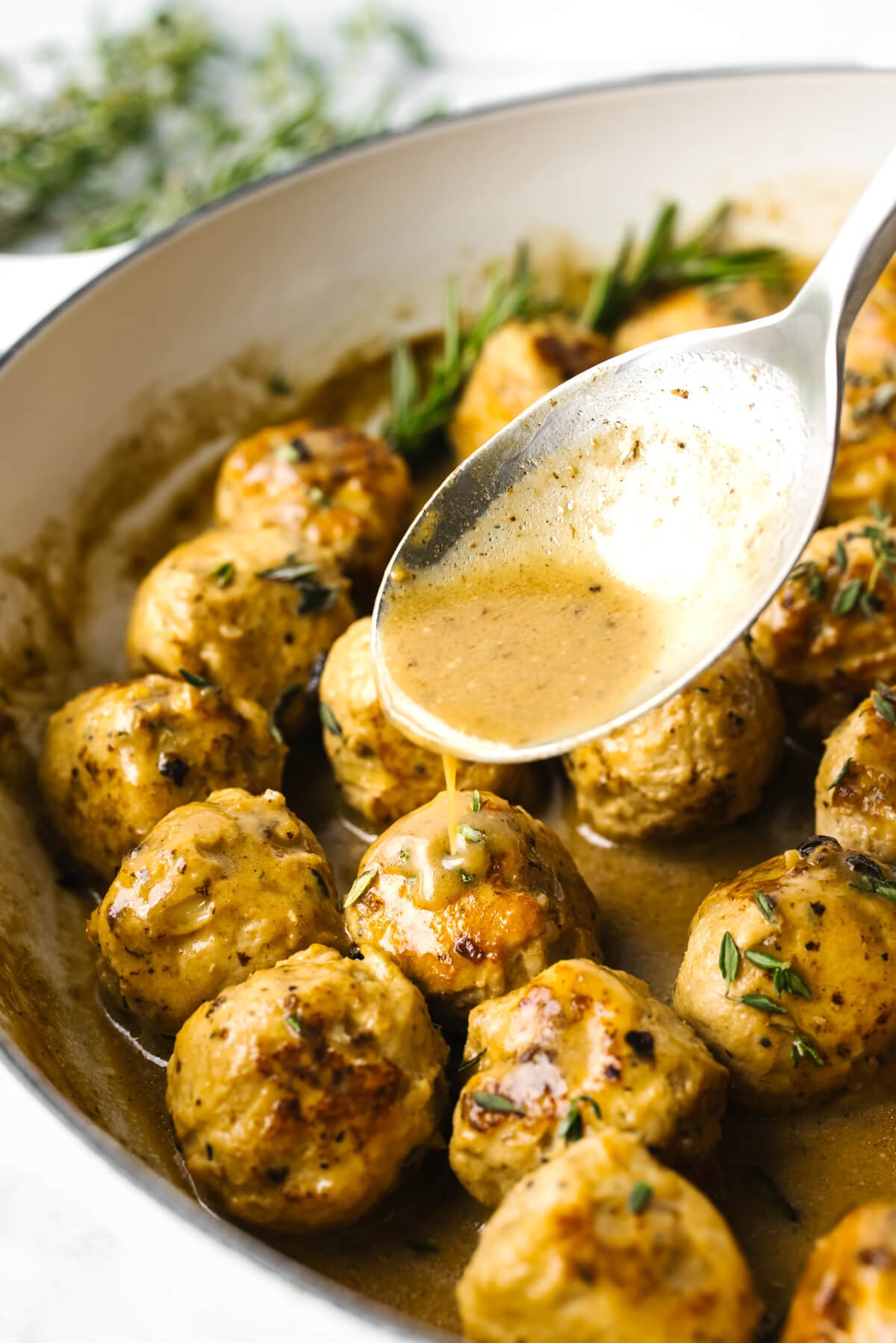 Pouring sauce over turkey meatballs with a spoon