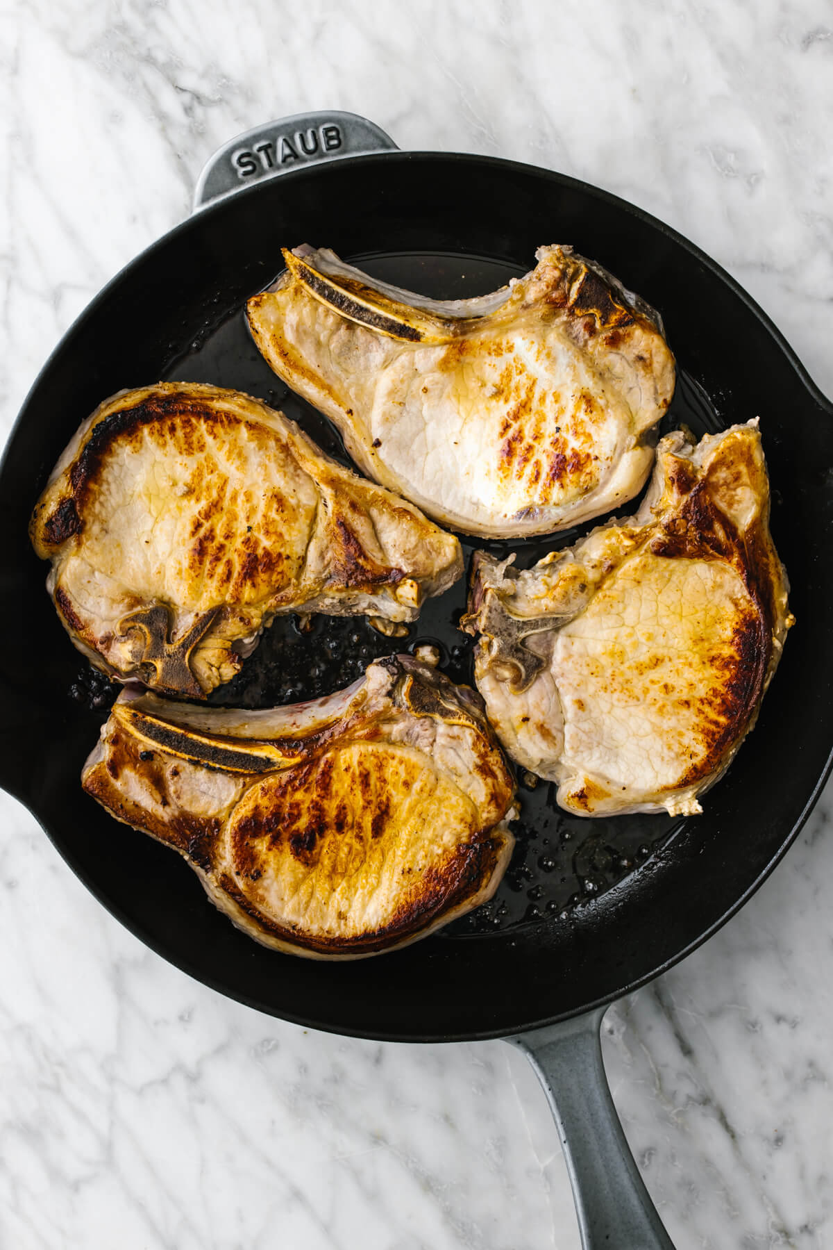 Searing pork chops in a skillet.