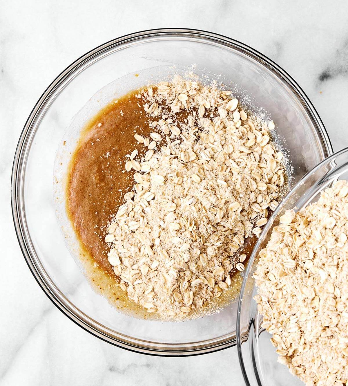 These are everything you want in a healthy oatmeal cookie! They're soft and chewy, perfectly spiced, and dotted with raisins. Adding oats into wet cookie dough mixture.