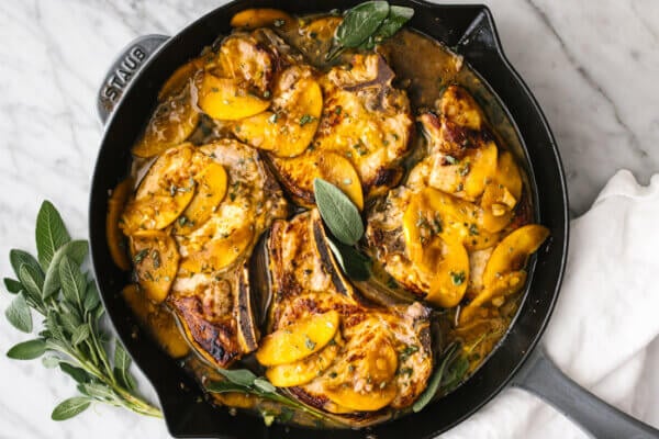 A skillet with apple cider sage pork chops.