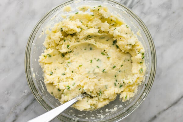 Stirring potato pancake mixture in a bowl.