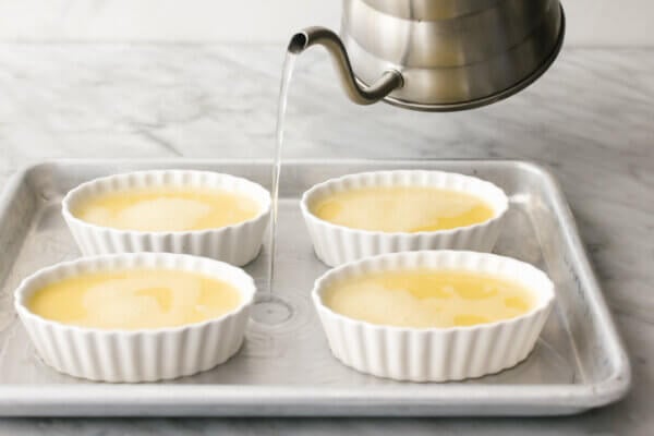 Pouring hot water into a tray of coconut crème brûlées