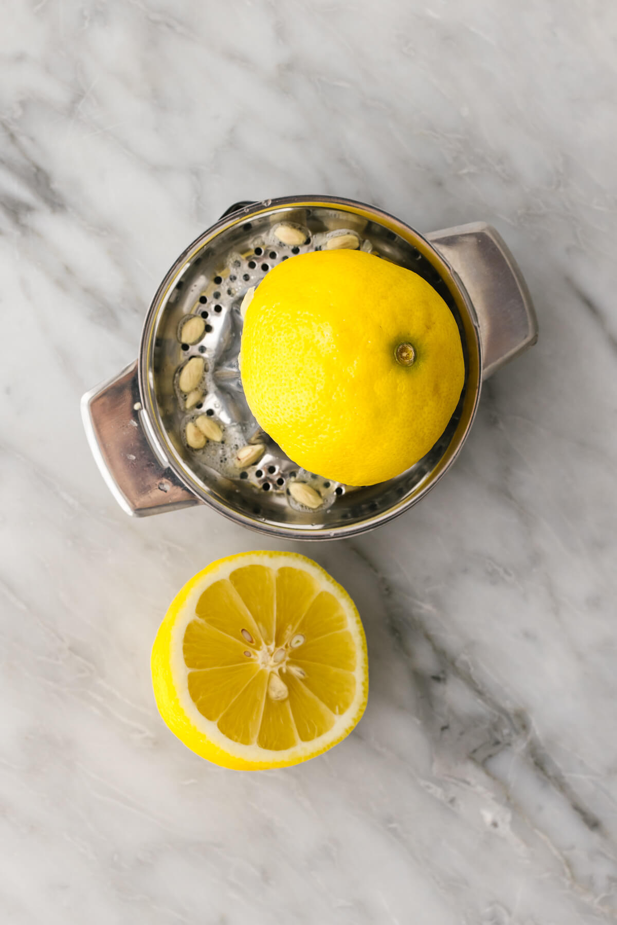 Juicing lemon with a metal juicer.