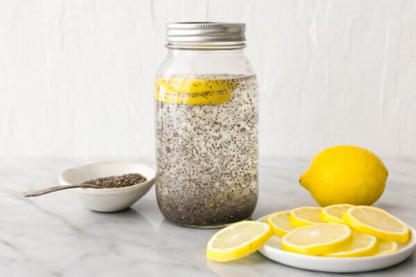 A table filled with chia seed water, lemon slices, and a bowl of chia seeds.