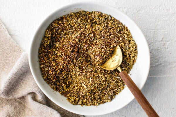 A bowl of za'atar spice with a gold spoon