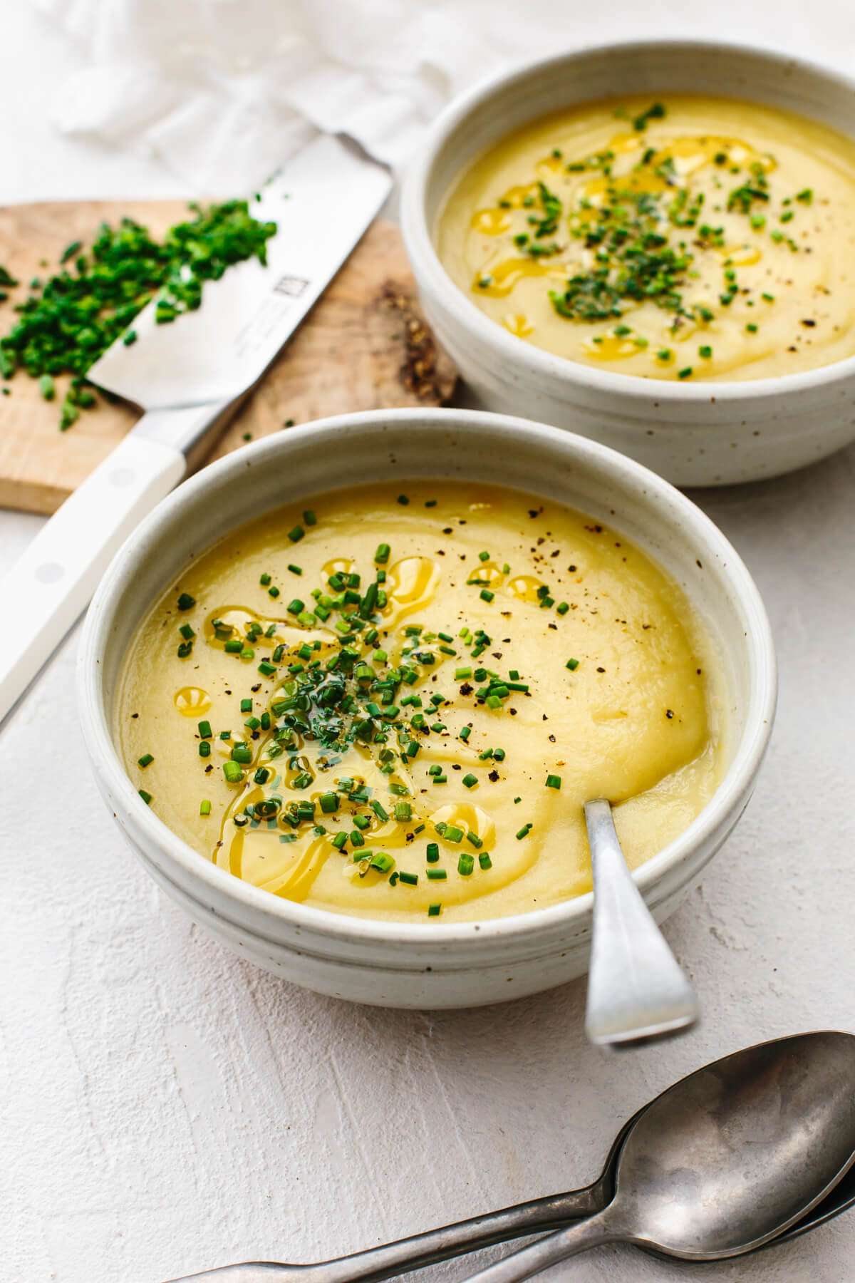 Bowls of potato leek soup next to chopped chives