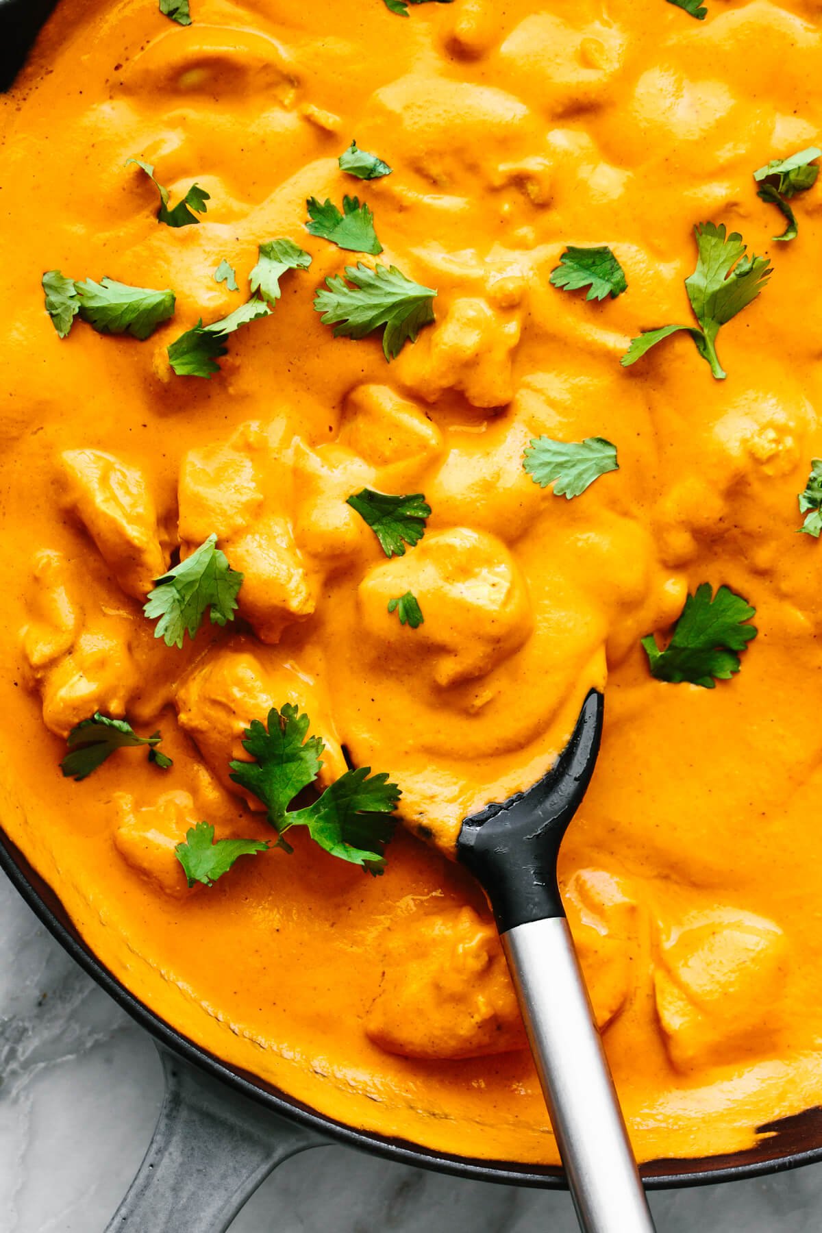 This butter chicken recipe is Indian comfort food at its best - with juicy spiced chicken tossed in a rich and velvety curry sauce. Creamy butter chicken in a pan with a serving spoon