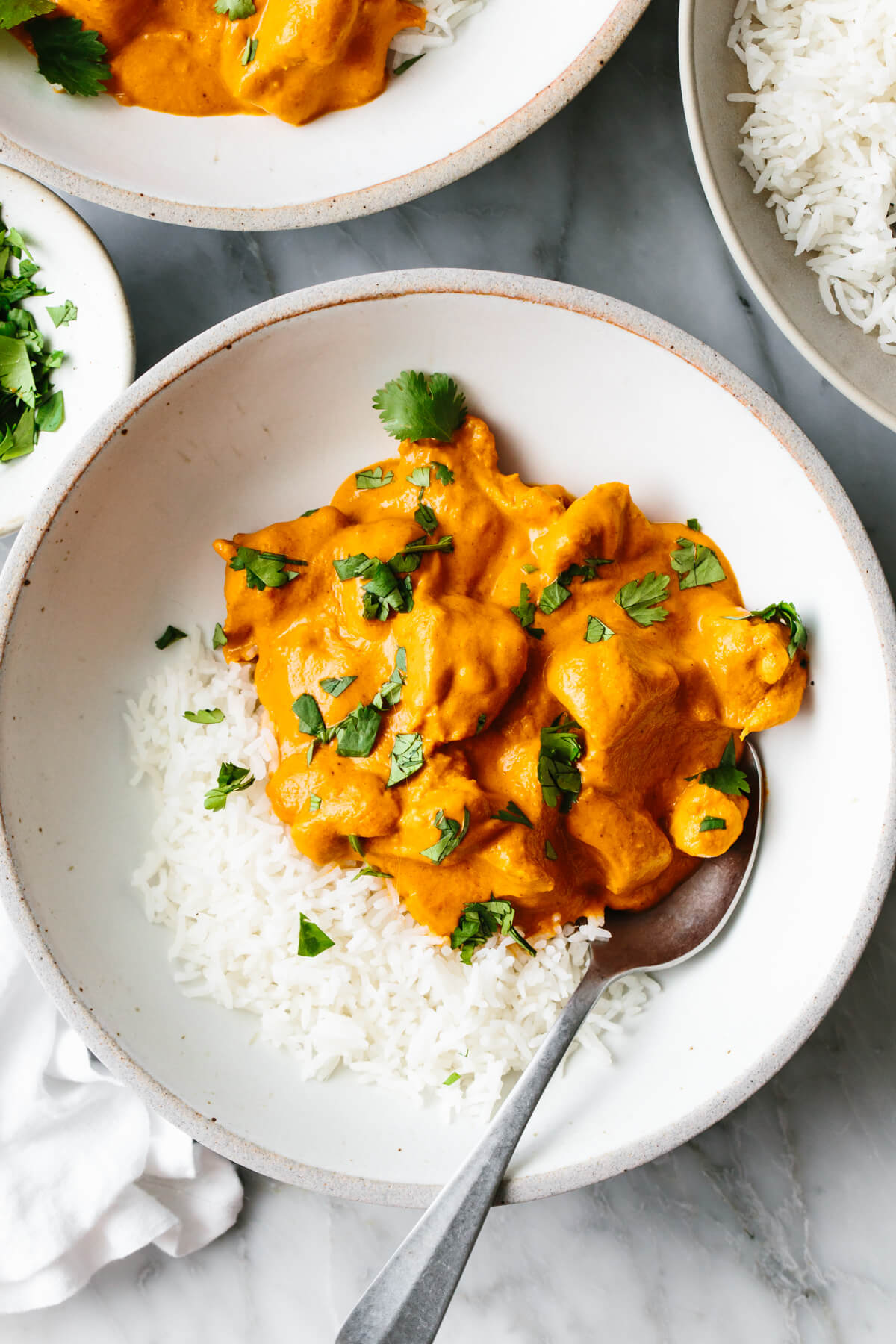 This butter chicken recipe is Indian comfort food at its best - with juicy spiced chicken tossed in a rich and velvety curry sauce. Butter chicken with rice in a bowl.