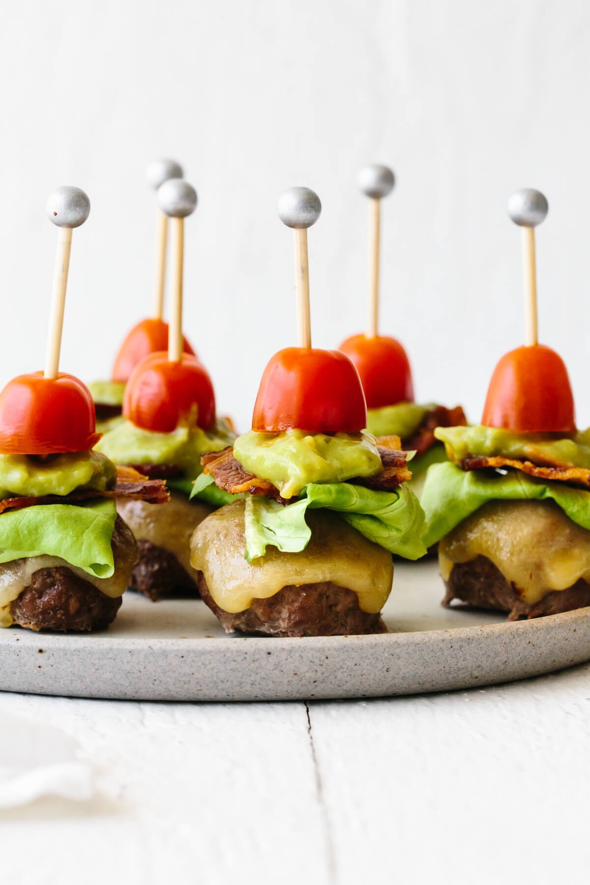 A plate filled with guacamole bacon burger bites